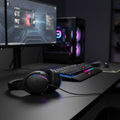 ASUS ROG Fusion II 300 gaming headset placed on a gaming desk with RGB-lit gaming setup in the background.