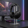 ASUS ROG Strix Go 2.4 wireless gaming headset on a stand in an RGB gaming room with blurred monitor background