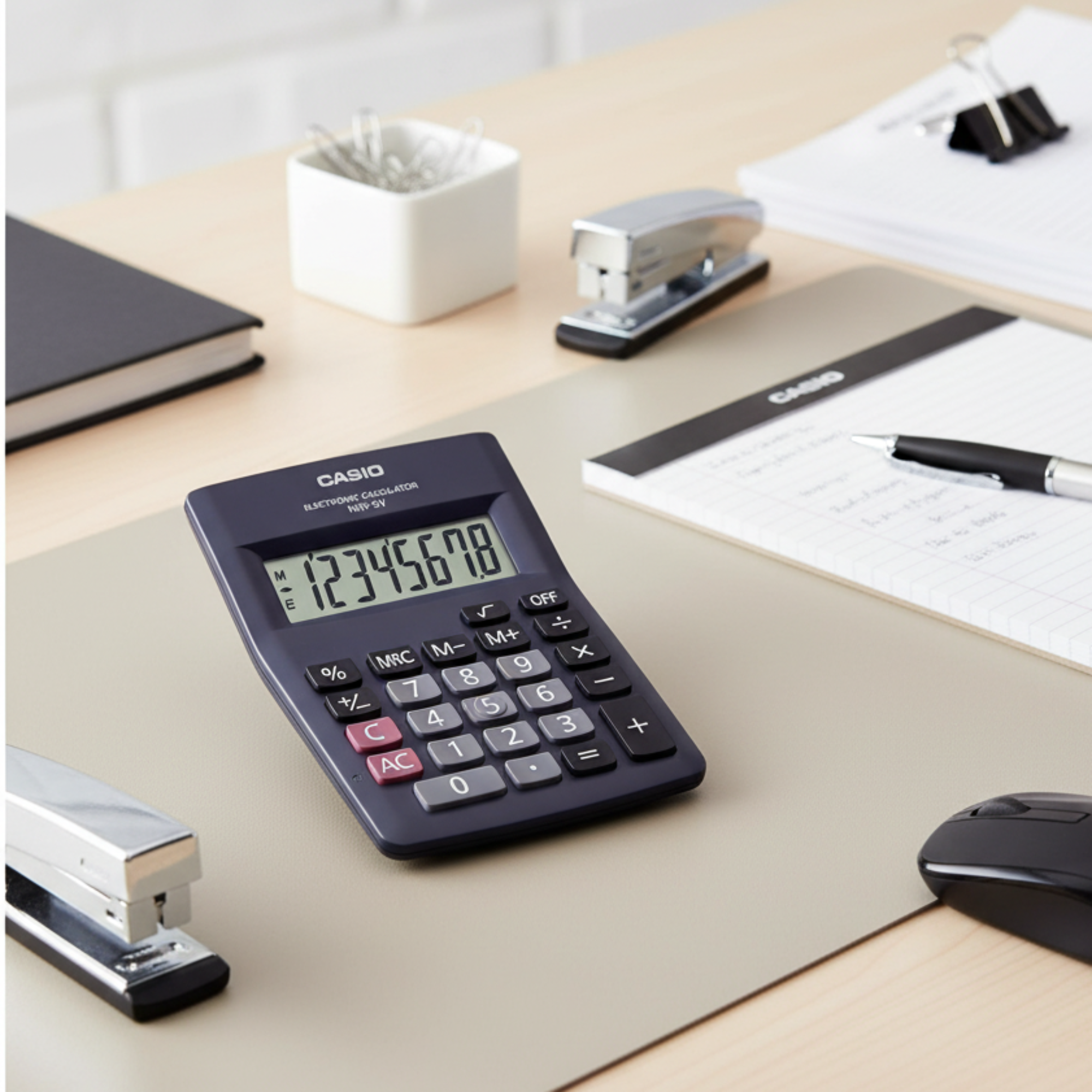 Casio MW-5V mini desk calculator on a modern office desk.

Black White