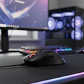 MSI GM50 gaming mouse centered on desk with blurred RGB gaming setup.