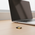 TP-Link UB500 Bluetooth adapter placed beside laptop in a real home office setup.